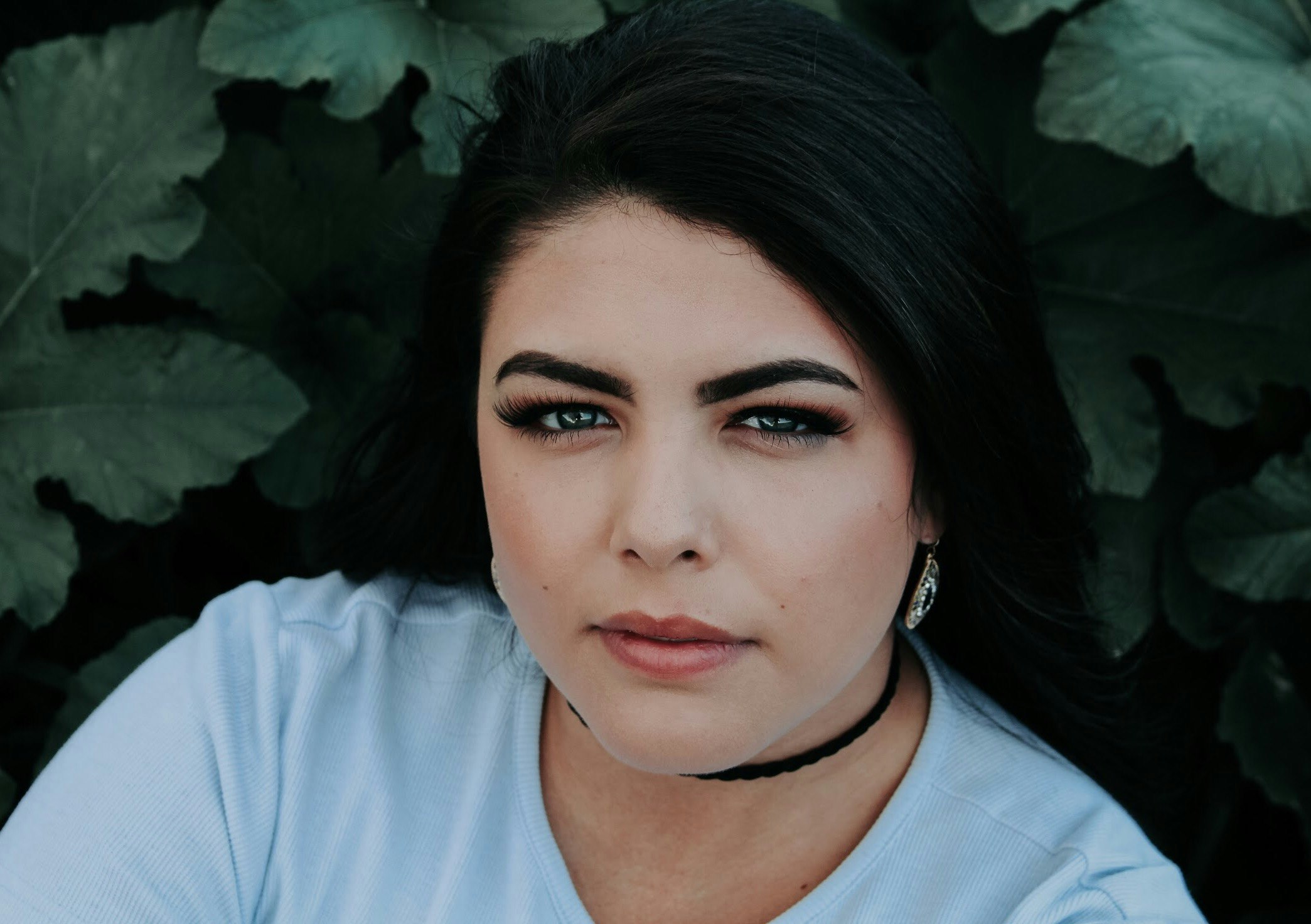 woman wearing blue top in front of green leaves